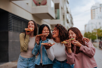 Friends laughing and eating pizza on the streets