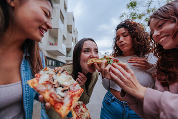 Friends enjoying their reunion by sharing pizza on the street