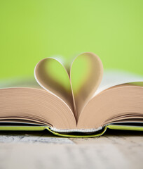 Heart from a book page on green background, book of love
