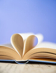 Heart from a book page on blue background, book of love
