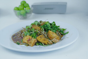 Sauted bean sprouts and tofu, sprinkled with cilantro leaves, served on a white plate.