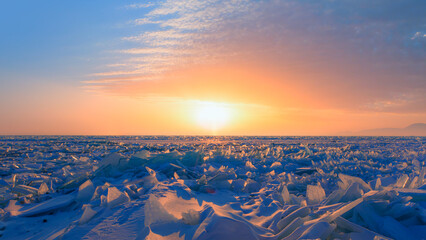Beautiful winter landscape of frozen Lake Baikal at sunrise - Snowy ice hummocks with transparent...