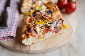 Homemade pizza with feta cheese, yellow squash, spanish duroc salami, onions and tomatoes on wooden...