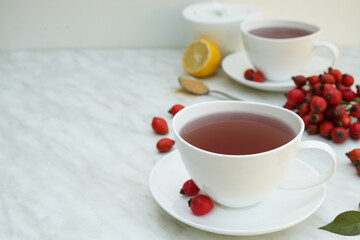 Hot vitamin tea with rose hips with a cup of tea, honey and lemon slices. Phytotherapy. Anti-cold drinks. Side view, copy space.
