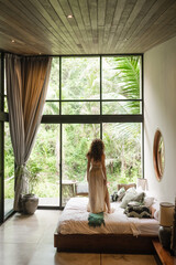 A girl of European appearance, with curly hair, greets the morning in a luxurious villa on the bed,...