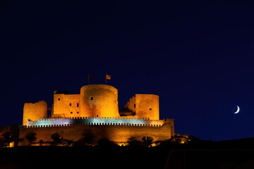 Obraz premium Night photo of the castle of Consuegra. Night landscape with the moon. Hill with mills and castle.