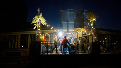 Beautiful young friends dancing on a rooftop concert, having fun and enjoying time together. Band with guitarist and drummer performing at a concert on party.