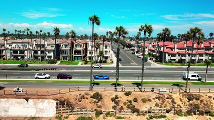 Panning left flying down PCH in Huntington Beach California with great views of traffic palm trees the bike path and Pacific Coast Highway.