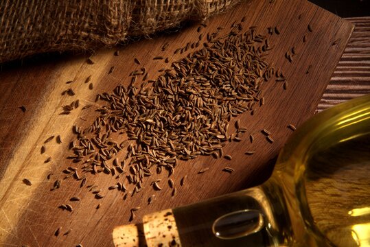 Cumin seeds scattered on a wooden cutting board, top view.