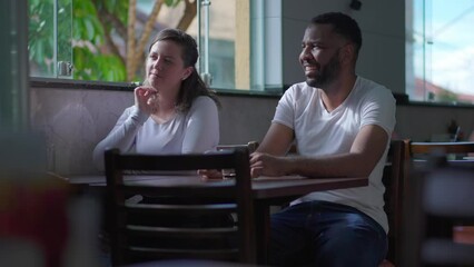 Candid Friends seated at cafeteria table in conversation. Diverse Brazilian people at restaurant meetup, lifestyle friendship
