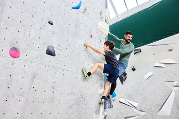 Dad and son climbing in a bouldering gym
