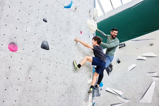 Dad and son climbing in a bouldering gym