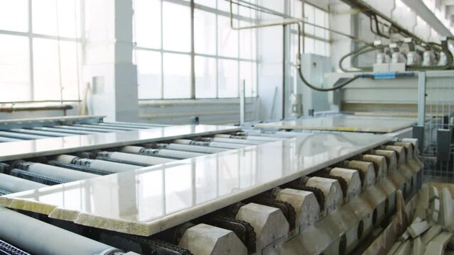 Full shot of white marble slab on conveyor of industrial machine in stone cutting factory with no people