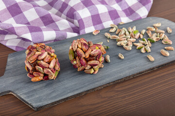 Turkish Dessert Cezerye with Hazelnut, Almond or pistachio. Turkish delight with carrot nuts atom cezerye dessert, white rustic wooden background. Traditional feast treat.