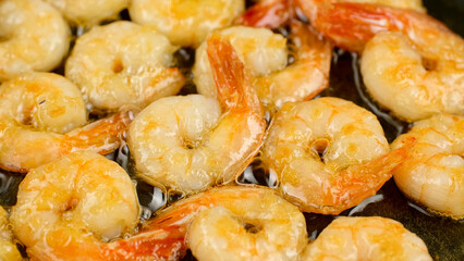 Chef roasts and tosses prawns in frying pan in restaurant kitchen. Cooking tasty seafood
