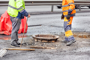 Repair of a sewer manhole on the carriageway during the reconstruction of a city street. - obrazy, fototapety, plakaty