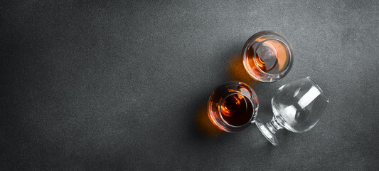 A glass with aged cognac or brandy on a dark table. Strong aged alcoholic drinks. On a concrete...