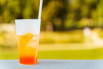 A glass with an Aperol Spritz cocktail and a straw in summer on the terrace. A refreshing summer drink