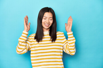 Asian woman in striped yellow sweater, joyful laughing a lot. Happiness concept.