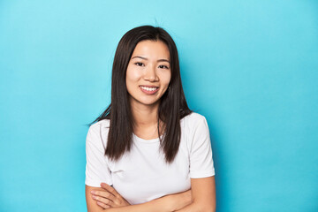 Fototapeta premium Young Asian woman in white t-shirt, studio shot, laughing and having fun.
