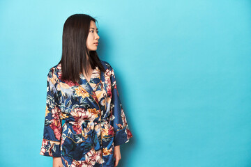 Elegant young Asian woman in floral kimono, studio backdrop.