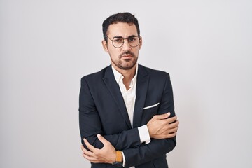 Handsome business hispanic man standing over white background shaking and freezing for winter cold with sad and shock expression on face