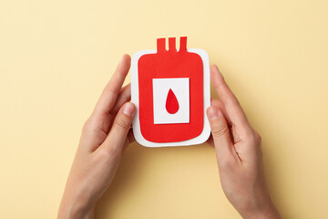 Paper container of blood in the hand on a light background. Blood donation