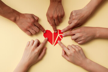 Red heart made of paper particles with hands on a light background. Blood donation