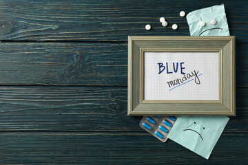 Text Blue Monday in photo frame, papers and pills on blue wooden background, space for text