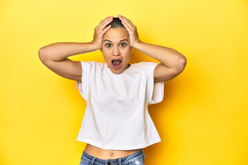 Shaved head woman in white tank top, yellow backdrop screaming, very excited, passionate, satisfied...