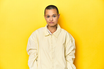 Fototapeta premium Young woman in jacket, yellow studio backdrop sad, serious face, feeling miserable and displeased.