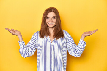 Business-dressed redhead, formal studio shot makes scale with arms, feels happy and confident.