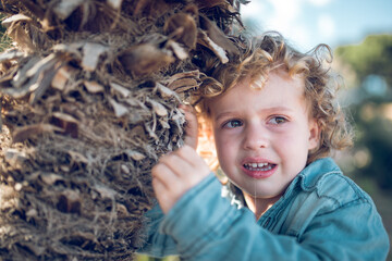 Crying boy near tree trunk
