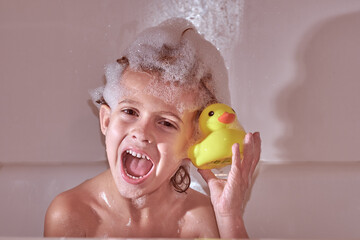 Happy boy with bath duck in bathtub