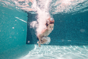 Little boy plunging in pool water - obrazy, fototapety, plakaty