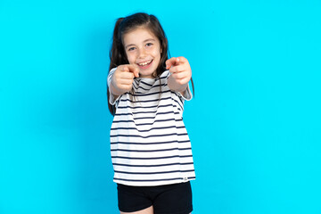 Fototapeta premium Caucasian kid girl wearing floral dress over blue background cheerful and smiling poiting at camera