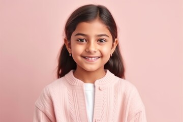 Portrait of a cute little girl smiling at the camera on a pink background