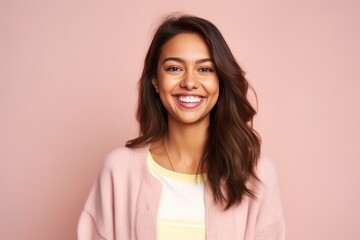 Fototapeta premium Portrait of a beautiful young woman smiling at camera isolated over pink background