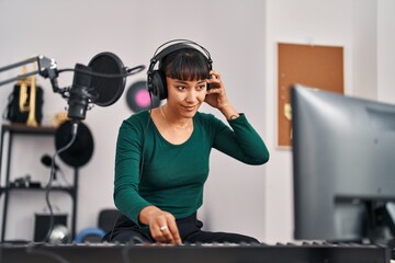 Young beautiful hispanic woman musician having dj session at music studio