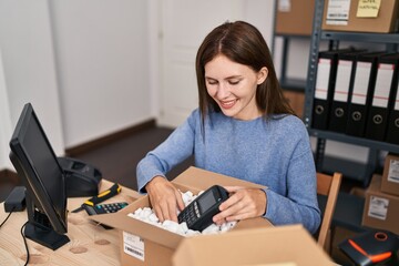 Young blonde woman ecommerce business worker packing data phone on cardboard box at office