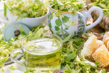 Linden flowers tea in a glass cup outdoors and cup with linden flowers, yellow drink of linden flower with linden blossoms honey in nature background, healthcare and healthy eating concept