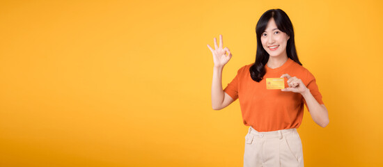 Attractive Asian lady confidently showing a credit card, emphasizing secure online shopping and financial transactions
