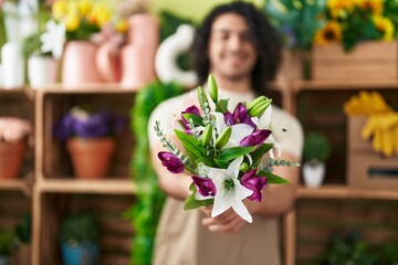 Young latin man florist holding bouquet of flowers at flower shop