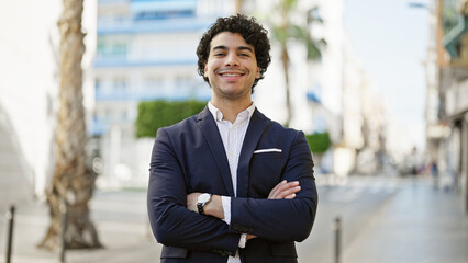 Young latin man business worker smiling confident standing with arms crossed gesture at street