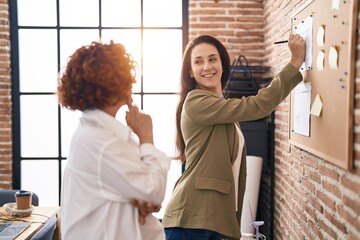 Obraz premium Two women business workers writing on cork board at office