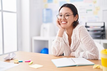 Young hispanic woman business worker smiling confident sitting on table at office