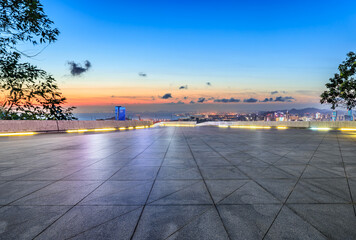 Empty square floor and city skyline by the sea at sunset