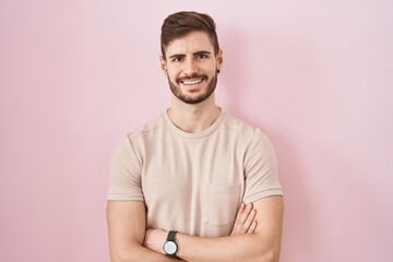 Hispanic man with beard standing over pink background happy face smiling with crossed arms looking at the camera. positive person.