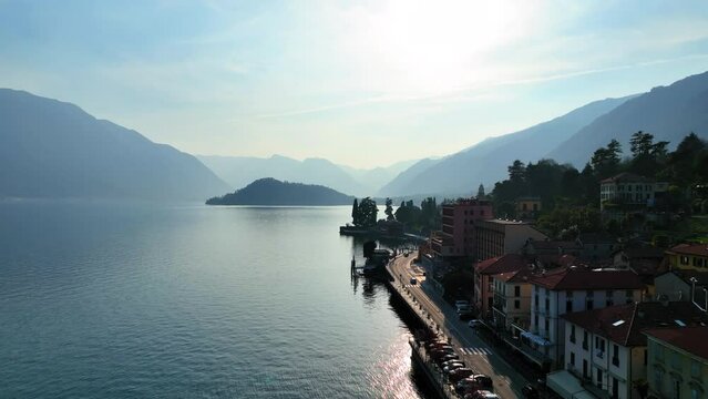 Aerial Forward Shot Of Vehicles On Road By Buildings And Lake Como Against Sky - Menaggio, Italy