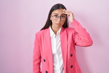 Young hispanic woman wearing business clothes and glasses worried and stressed about a problem with hand on forehead, nervous and anxious for crisis